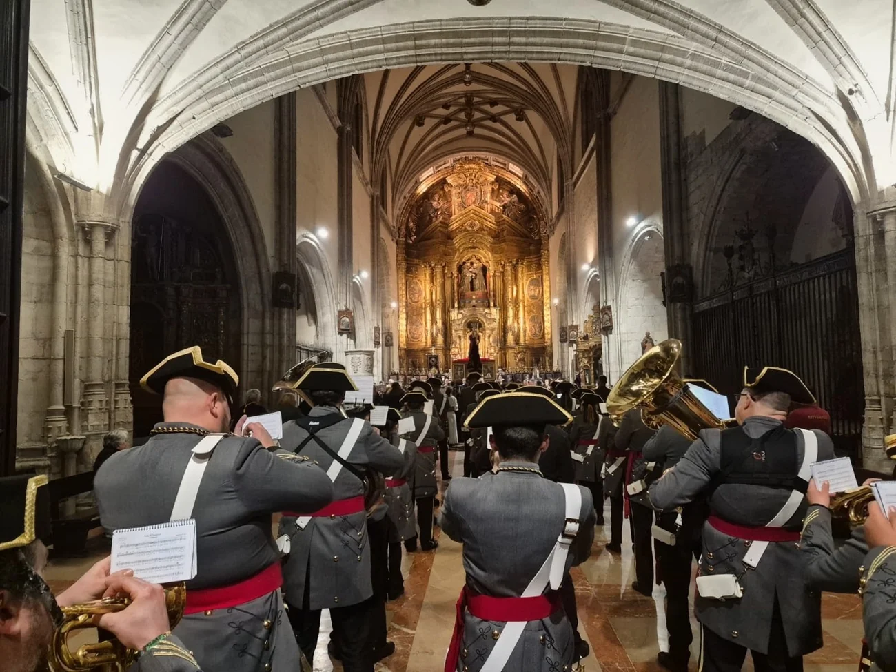 Desde detrás de la agrupación, la nave del templo se abre hacia el retablo dorado.
