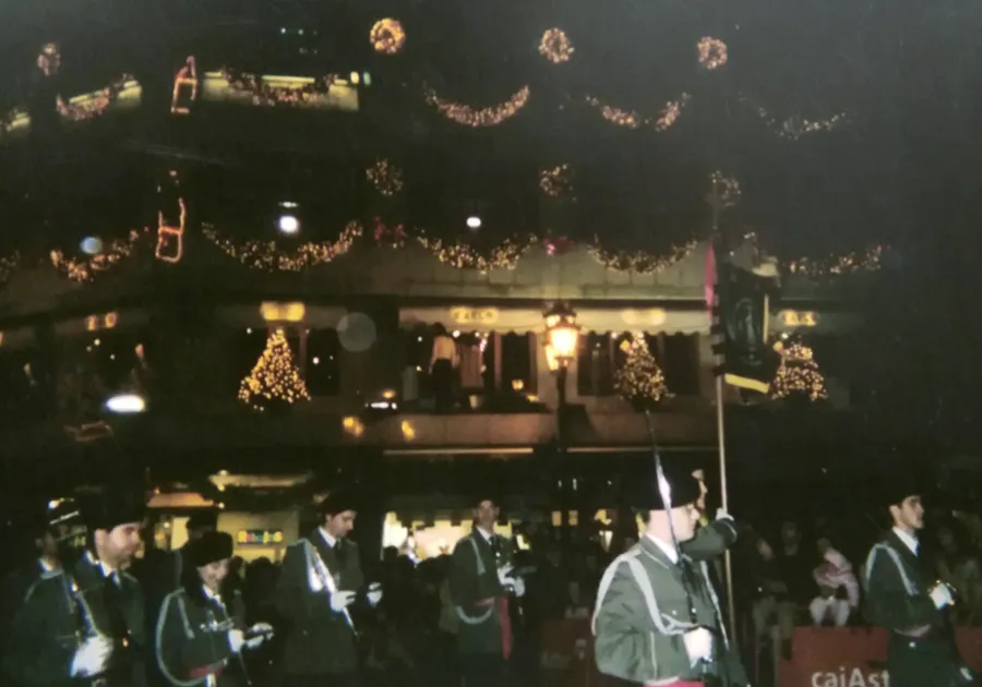 La agrupación toca de noche en la Cabalgata de Reyes de Oviedo, con las luces de Navidad al fondo.