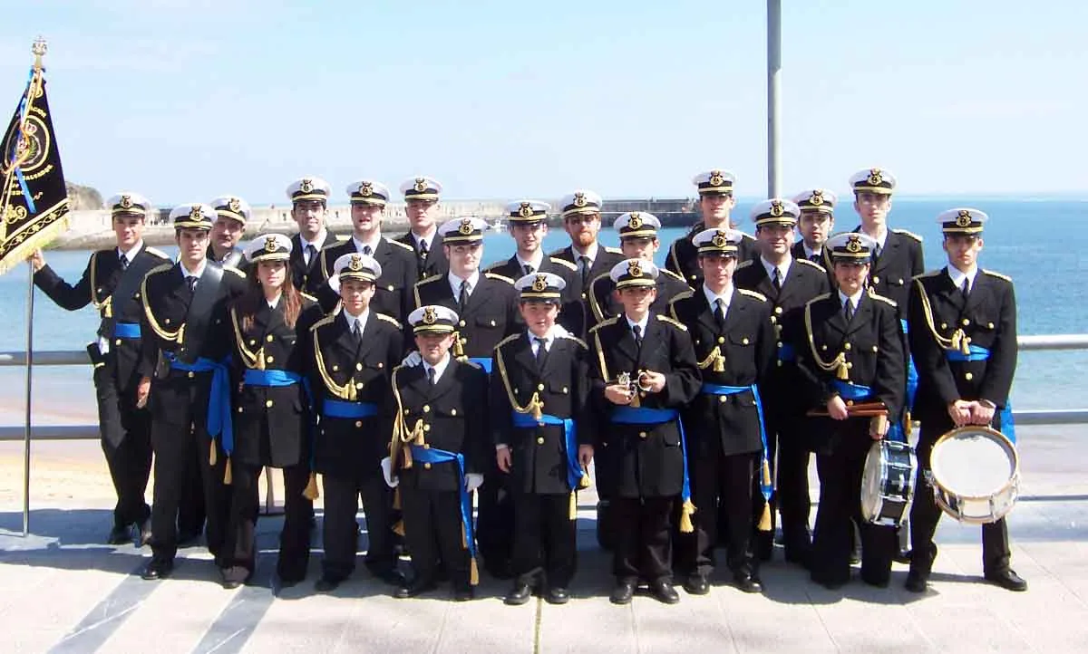 Foto de grupo de la agrupación junto al mar en Luanco, con el uniforme azul y blanco de 2003.