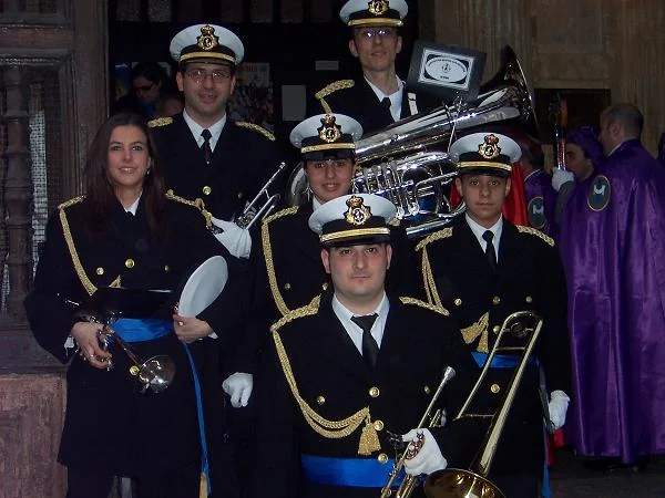 Un grupo de músicos posa con sus instrumentos en plena calle durante una procesión nocturna.